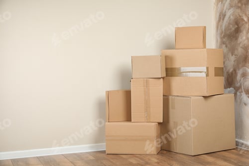 Preview: Pile of cardboard boxes near light wall indoors. Space for text
