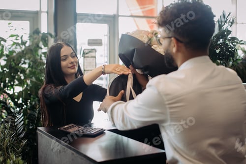 Preview: Flower shop assistant giving bouquet to man customer