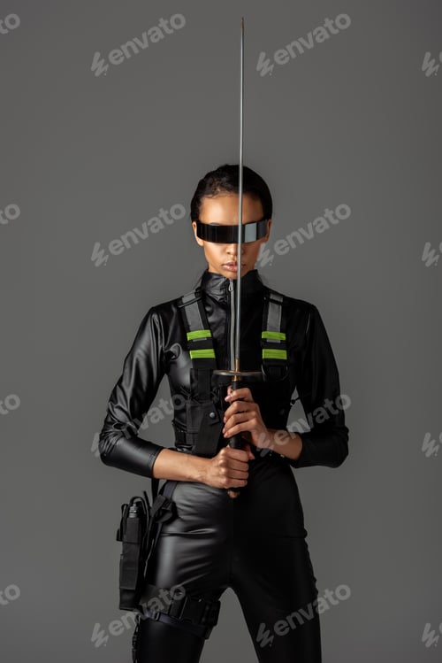 Preview: attractive futuristic african american woman in glasses with sword isolated on grey
