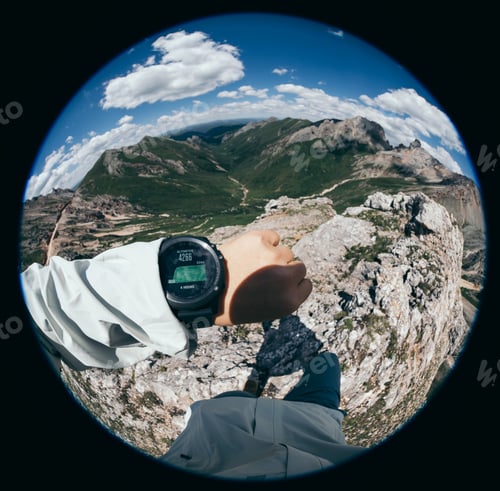 Preview: Hiker on high altitude mountain top checking the altimeter on the sports watch