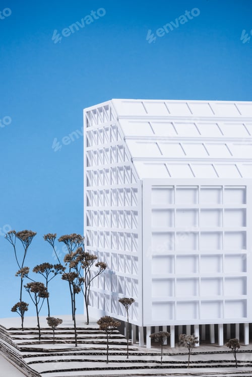 Preview: close up view of white building model with miniature trees on blue background