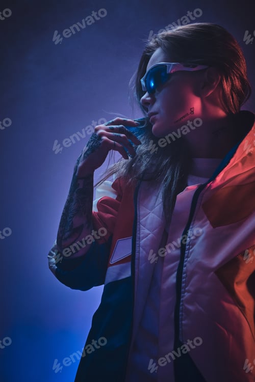 Inked attractive female posing in a neon vivid lights of a studio surrounded by smoke