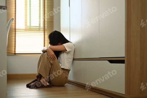 Preview: Upset teenage girl sitting on floor feeling lonely and sad. Psychological and mental health concept