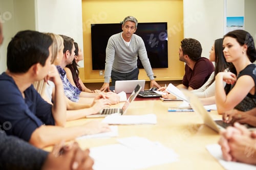 Preview: Male Boss Addressing Meeting Around Boardroom Table