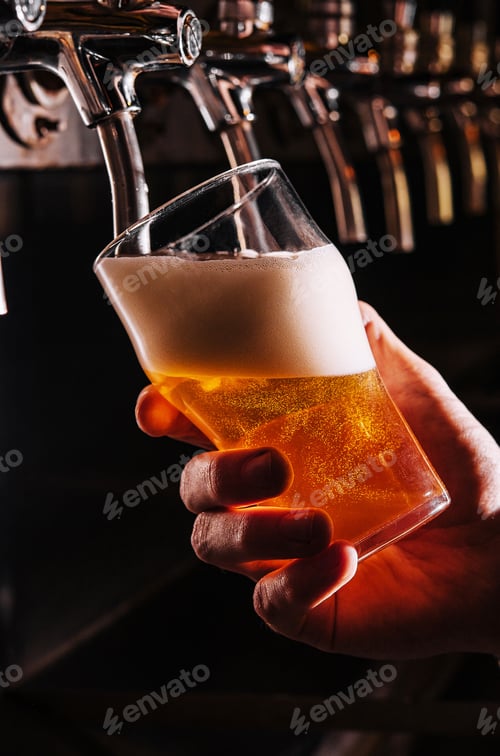 Preview: Close-up of barman hand at beer tap pouring a draught lager beer