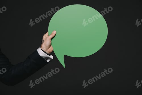 Preview: cropped view of man holding green speech bubble in hands isolated on black