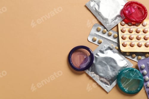 Preview: Blisters of contraceptive pills and condoms on beige background, flat lay. Space for text
