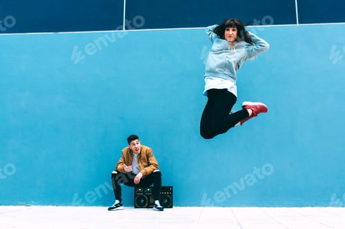 Preview: Young happy couple dancing on the street with a vintage radio cassette stereo