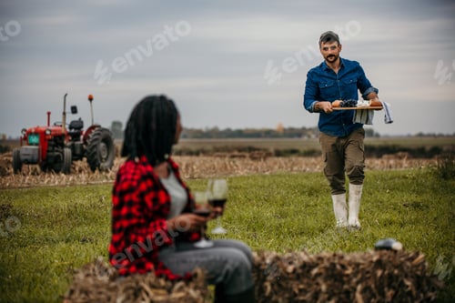 Preview: Farmer bringing food to woman sitting on hay bale in farm field
