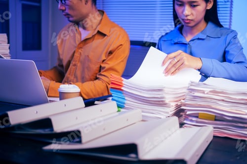 Preview: A businessman and woman are working overtime at their desks office at night.They are busy,stressed
