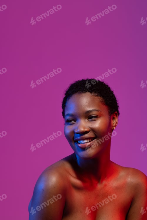 Preview: African american woman looking away smiling, in blue and red light on purple background, copy space