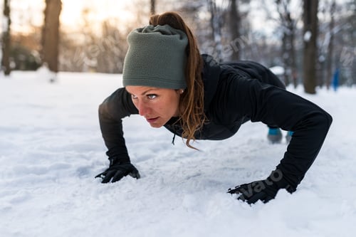 Preview: Female athlete exercising in park in winter
