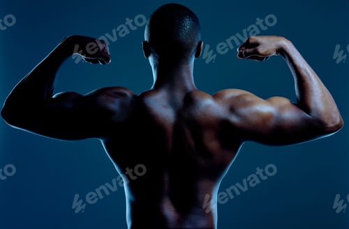 Preview: Gotta love those guns. Rearview studio shot of a fit young man flexing against a black background.