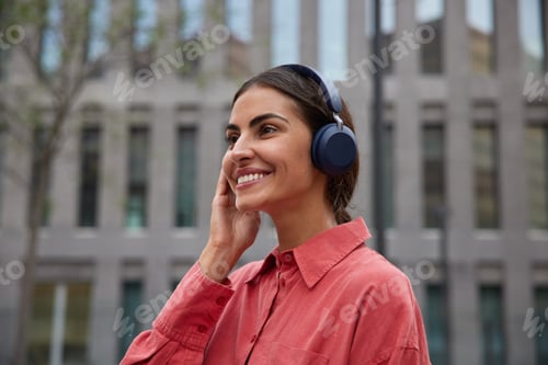 Preview: Horizontal shot of beautiful pleased dark haired woman focused into distance smiles broadly dressed