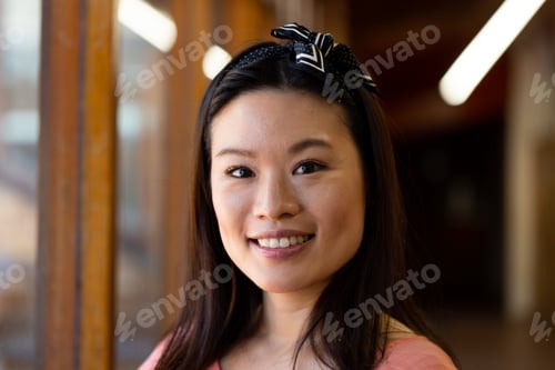 Preview: Portrait of happy asian female teacher with band at school corridor
