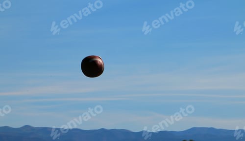Preview: Background of football spiraling through the air against blue sky.