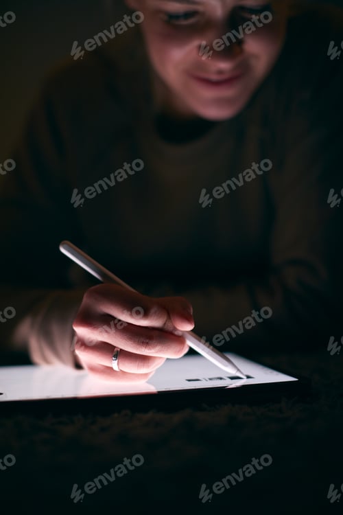 Preview: Close Up Of Woman Drawing On Digital Tablet Using Stylus Pen Lying On Carpet At Night