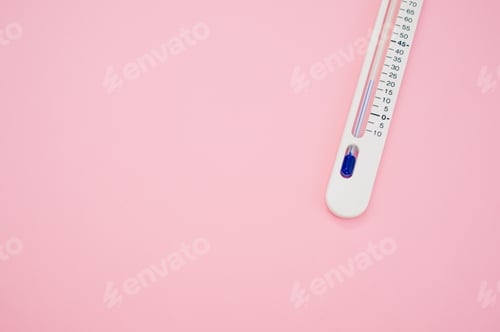 Preview: Top view closeup of an easy read thermometer placed on a pink background