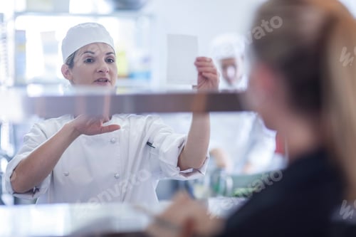 Preview: Chef taking orders from waitress in kitchen