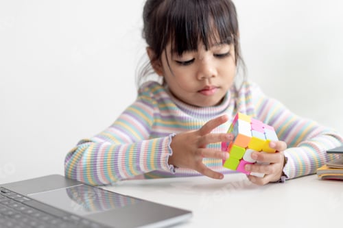 Preview: Asian little cute girl holding Rubik's cube in her hands. Rubik's cube is a game that increases the