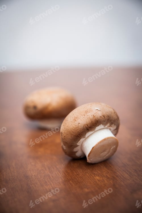 Two Brown Mushrooms on a Wooden Surface
