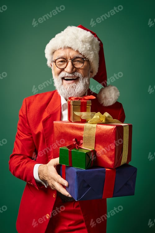 Preview: portrait of elegant Santa in red attire holding bunch of presents smiling at camera, winter concept
