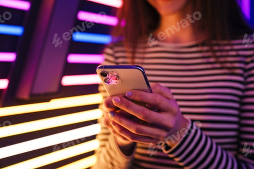 Preview: Young brunette woman in striped long sleeve using mobile phone