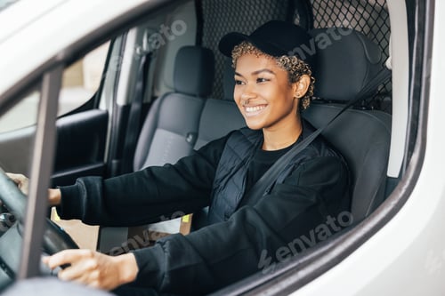 Preview: Portrait of a young woman working for a delivery service, sitting on a driver's seat