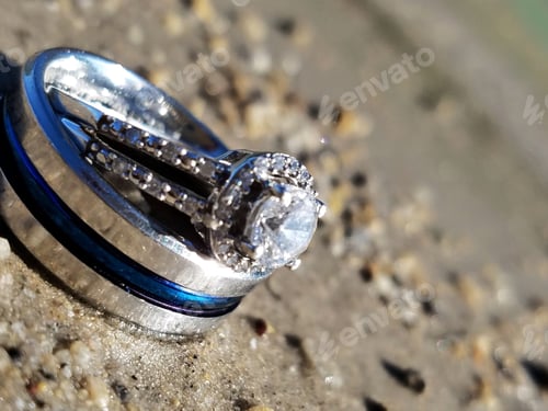 Preview: Wedding rings on a beach in the sunlight.