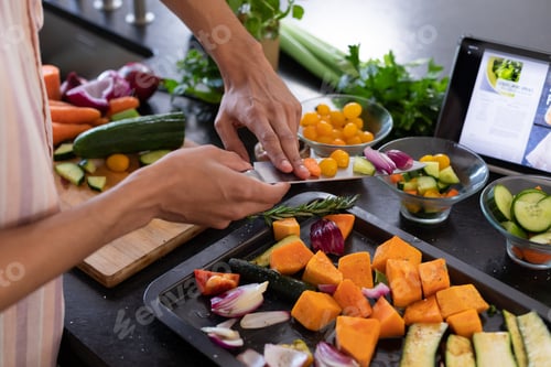Preview: Midsection of biracial man cooking, chopping vegetables in kitchen