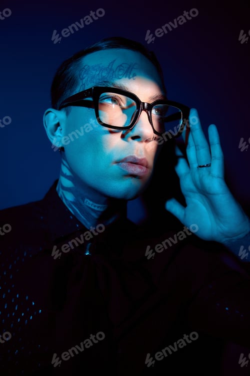 Preview: Young man in stylish attire gracefully poses against a vivid blue backdrop