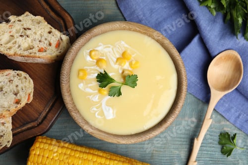 Preview: Delicious corn cream soup served on light blue wooden table, flat lay