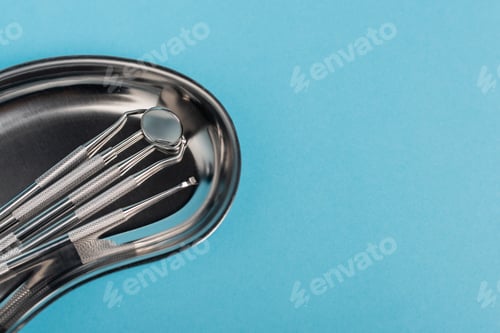 Preview: Set of dental tools in metal tray on blue background