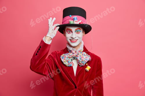 Preview: Positive mad hatter keeps hand on hat smiles happily takes part in carnival dresses for halloween pa