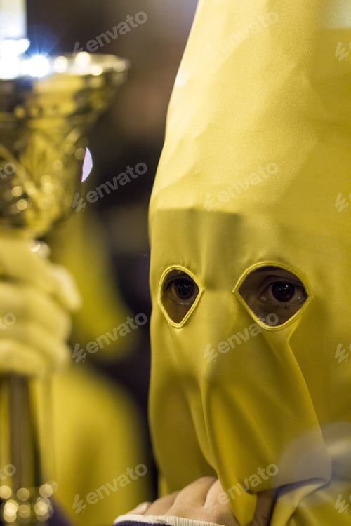 Preview: Vertical shot of a priest wearing a yellow mask with only their eyes visible