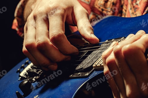 Preview: Close up of male hand playing electric guitar in the dark