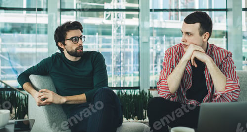 Preview: Cheerful colleagues discussing business project in cafe