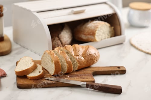 Preview: Wooden bread basket with freshly baked loaves and knife on white marble table in kitchen
