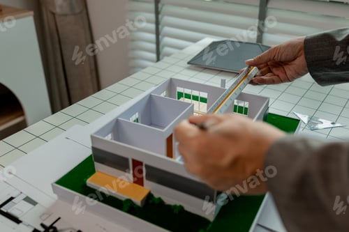 Preview: An architect works in the office, an engineer is using a tool to take measurements of a house model