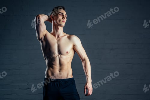 Preview: sexy naked man without clothes demonstrates the abs muscles on a dark background