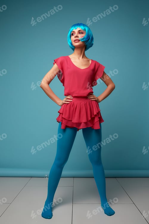 Preview: Close up of a flirtatious female model on blue background wearing a blue wig. Pretty glamorous woman