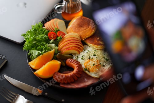 Preview: Breakfast pancakes, fried eggs, sausages, ham and fruit.