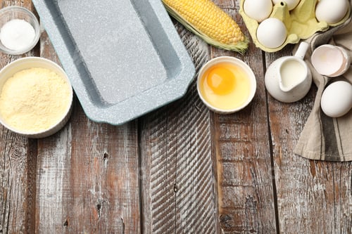 Preview: Making cornbread. Different ingredients and baking dish on wooden table, flat lay. Space for text