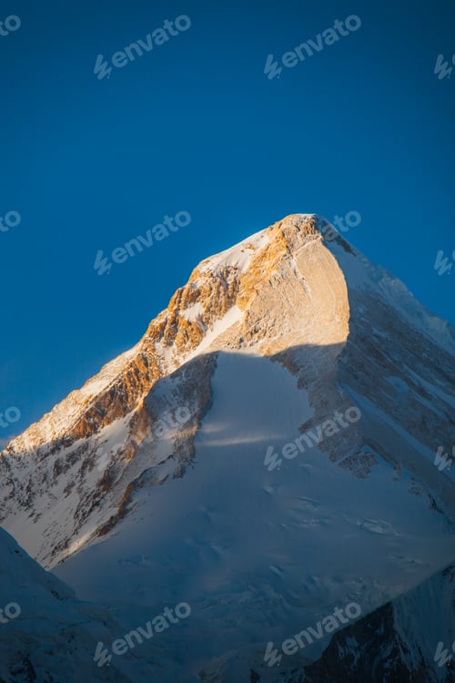 Preview: Snowcapped mountain peak in golden hour sunlight