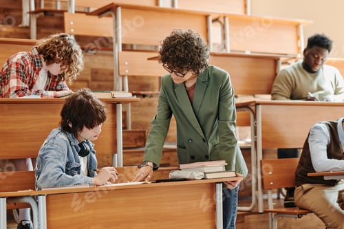 Preview: Teenage student looking at her notes while teacher consulting her about task