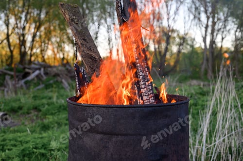 Preview: garbage incineration in rusty metal barrel. burning branches and old grass from the land plot