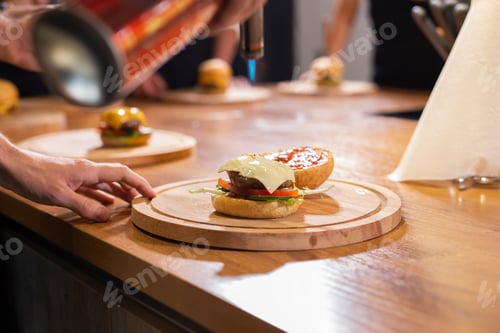 Preview: Preparing delicious burgers. Chef cooking meat burgers with beef, cheese and vegetables. Close-up