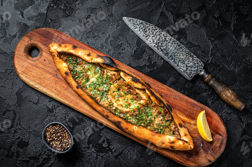 Preview: Turkish pide pie with beef meat and vegetables. Black background. Top view
