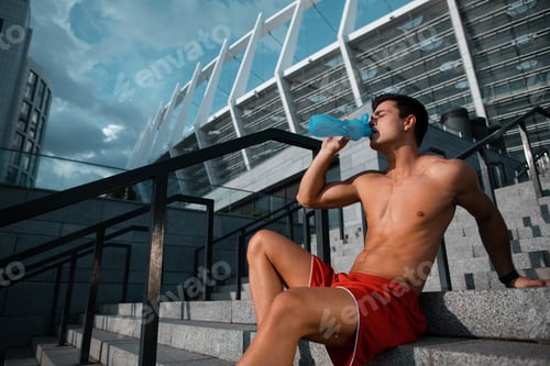 Preview: Side View Calm Stripped To Waist Young Male Athlete Tasting Appetizing Liquid While Relaxing After