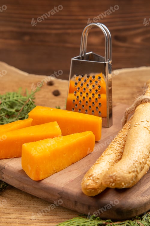 Preview: bottom view slices of cheese bread grater on chopping board pine tree branches on wooden table
